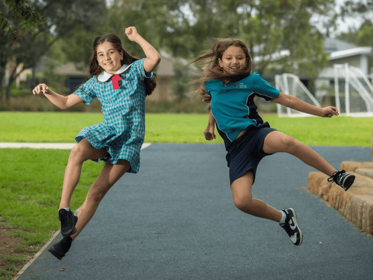 Two students leaping on a footpath