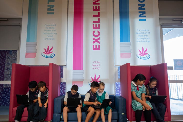 Seven students seated on flexible seating lounges with the school banners - integrity, excellence and innovation, hanging behind them