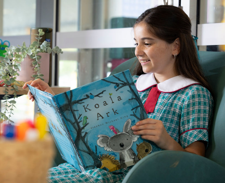 A girl reads a book on a winged armchair