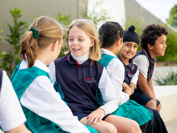 Five students are sitting next to each other, smiling and talking.