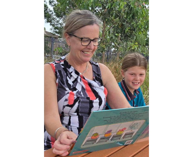 Mrs Crawford with a book, seated next to a student