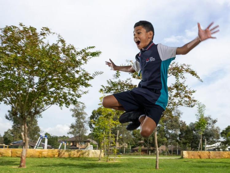 A student leaping in the air with arms outstretched and knees to the side
