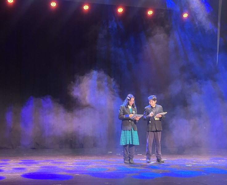 Two student leaders on a performing arts stage with dramatic lighting and smoke effects