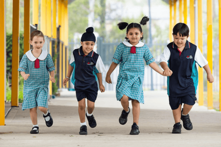 Four students running towards the camera along an outdoor corridor