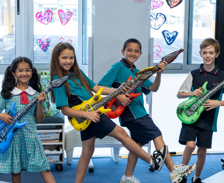 Four students pretending to play inflatable electric guitars